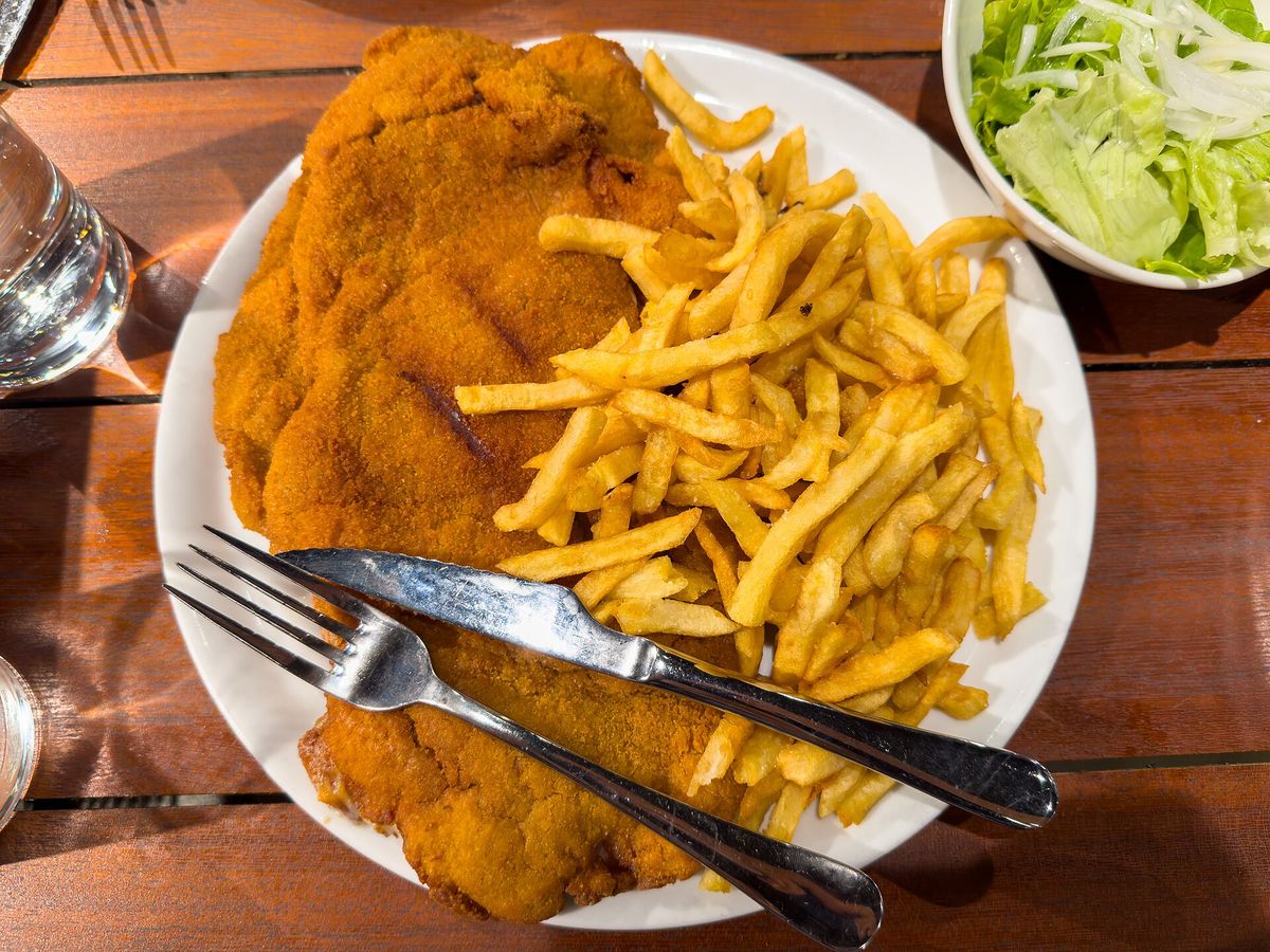Cachopo empanado con patatas fritas y ensalada, visto desde arriba